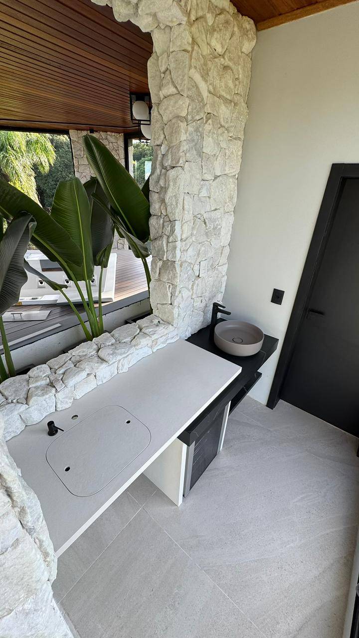 Área gourmet com bancada em lâmina ultracompacta, iluminação quente e marcenaria em madeira.